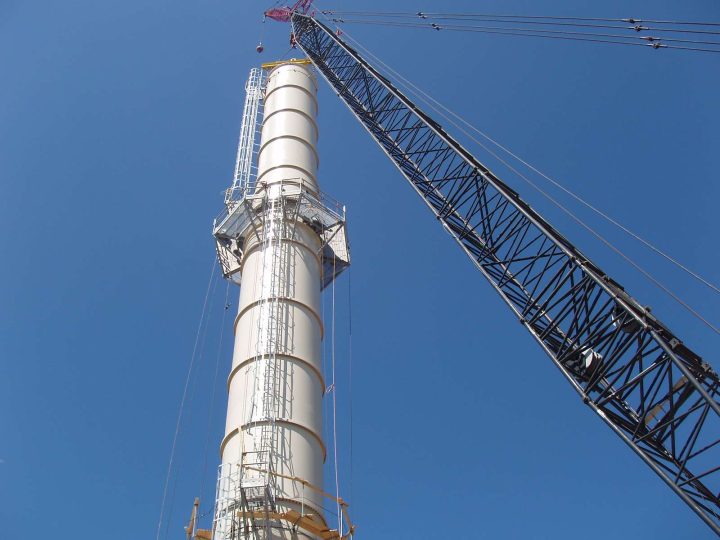 Large industrial chimney stack being erected by crane
